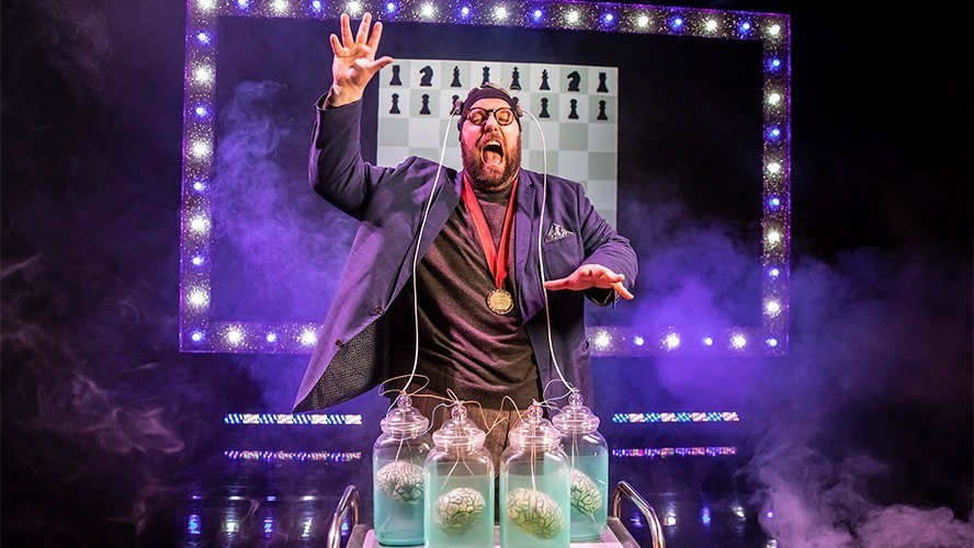 A dramatic stage scene featuring performers in elaborate costumes and vibrant lighting during a show.