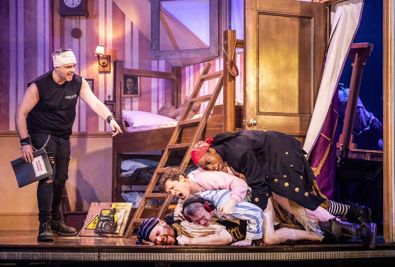 A theatrical scene from "Peter Pan Goes Wrong" featuring actors in colourful costumes on stage.