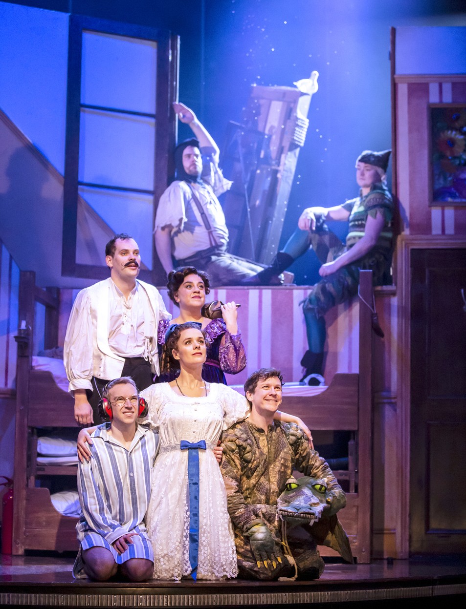 Actors performing a scene from "Peter Pan Goes Wrong" on stage, with vibrant costumes and dramatic lighting.