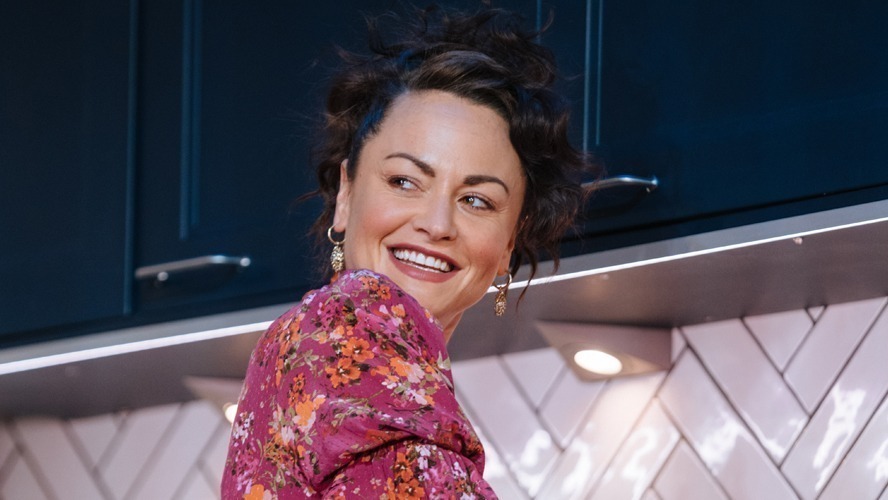 Jaime Winstone as Jenny, standing in a dimly lit room with atmospheric shadows.