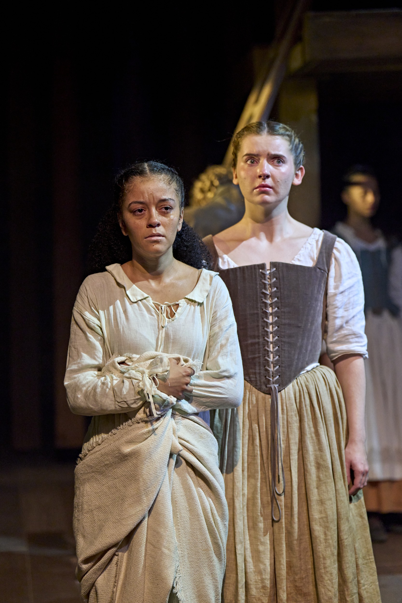 London cast of Hamnet performing on stage, with dramatic lighting and period costumes.