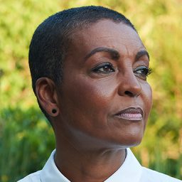 Adjoa Andoh performing on stage in a theatrical setting, with dramatic lighting and focused expression.