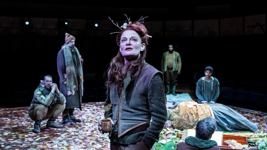 A vibrant stage scene with actors performing in period costumes under dramatic lighting.