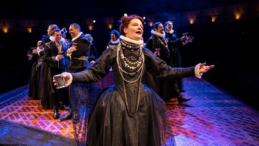 A stage set with vibrant lighting, featuring actors in period costumes performing a scene.