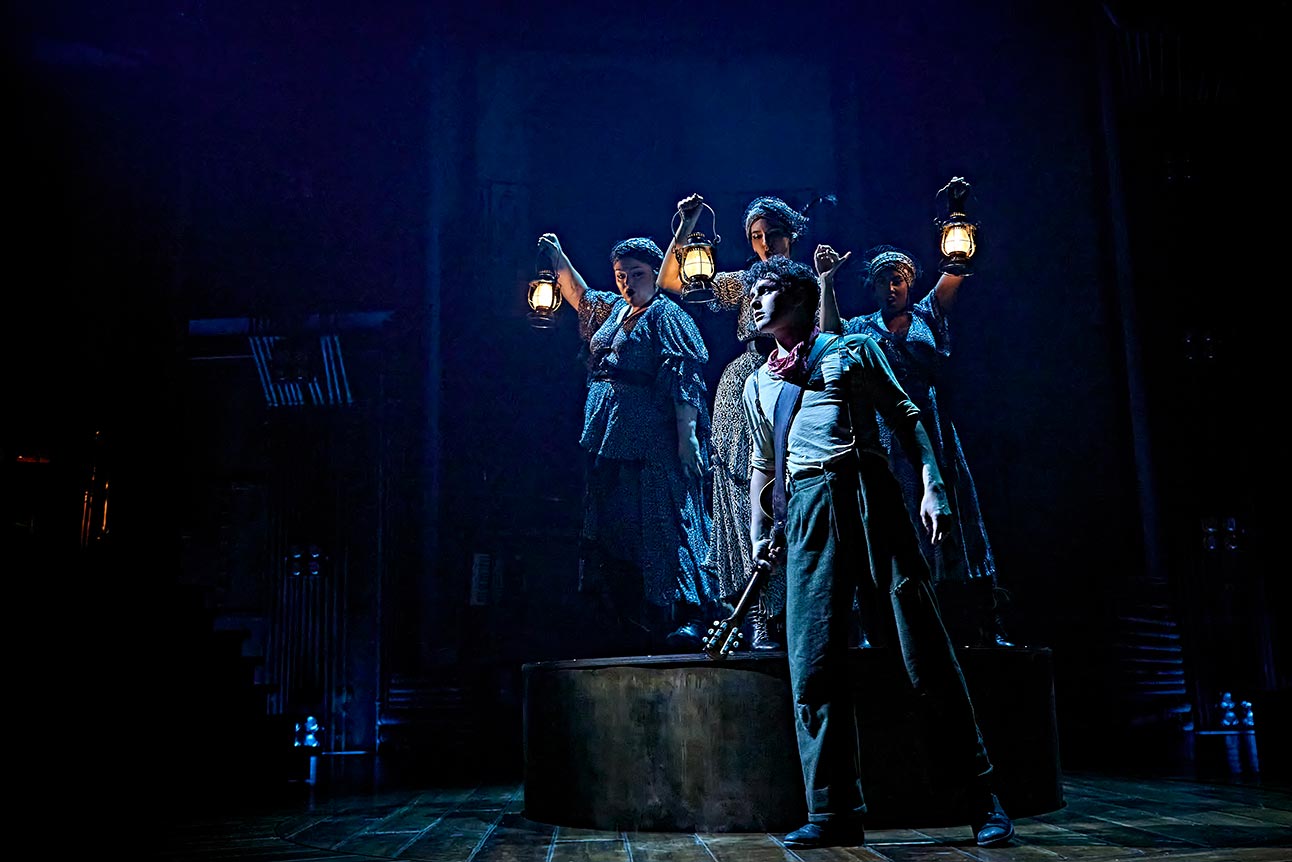 Allie, Daniel, Melanie, Dylan, and Lauran perform on stage in Hadestown, dressed in colourful costumes with dramatic lighting.