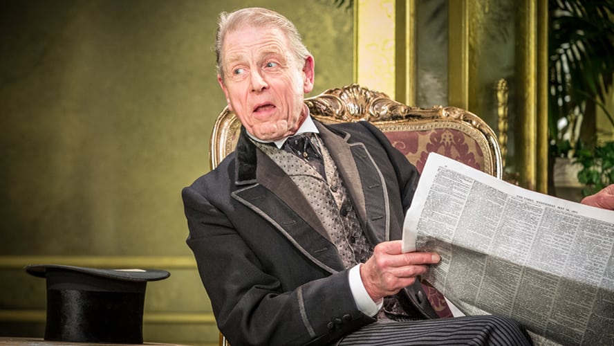 A stage scene from "An Ideal Husband" featuring actors in period costumes and elegant set design.