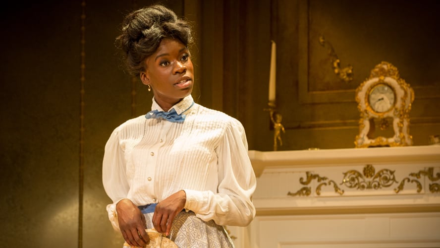 A stage scene from "An Ideal Husband" featuring actors in period costumes and elegant set design.