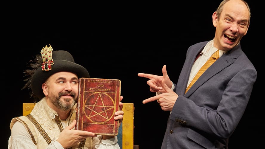 A vibrant stage scene featuring actors in historical costumes, with dramatic lighting and props.