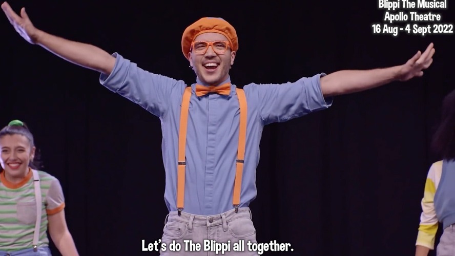 Blippi in a colourful outfit, dancing joyfully with children in a bright, cheerful setting.