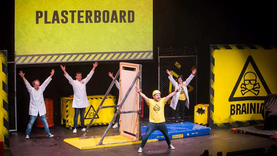 A stage set with bright lights, colourful props, and performers engaging the audience.
