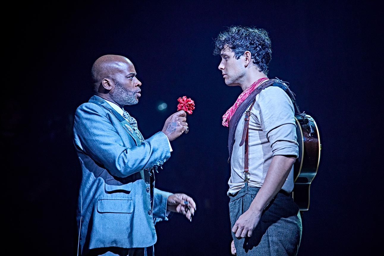 Cedric Neal offers a red flower to Dylan Wood, dressed in a grey suit and casual attire.