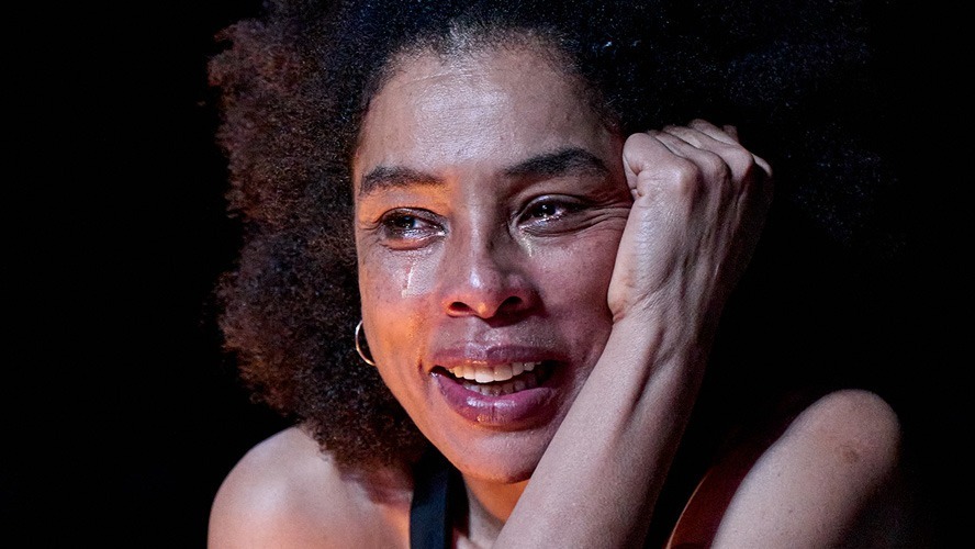 Sophie Okonedo as Medea, with intense expression, wearing a dark costume against a blurred background.