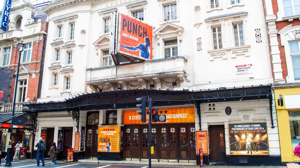Apollo Theatre exterior with illuminated marquee, showcasing vibrant lights and a bustling street scene.