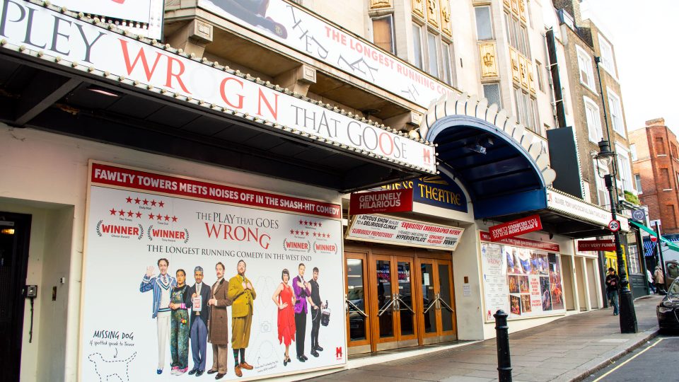 Duchess Theatre entrance featuring a vibrant poster for "The Play That Goes Wrong" and blue awning.