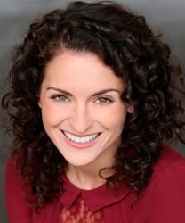Danielle Bird smiling, wearing a blue blouse, with shoulder-length brown hair and a neutral background.