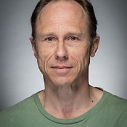 David Annen in character costume, standing on stage with dramatic lighting and a focused expression.
