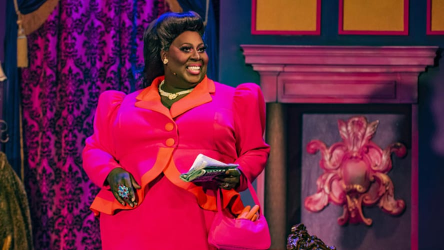 A performer executing a dramatic death drop on stage, wearing a vibrant costume and dramatic makeup.