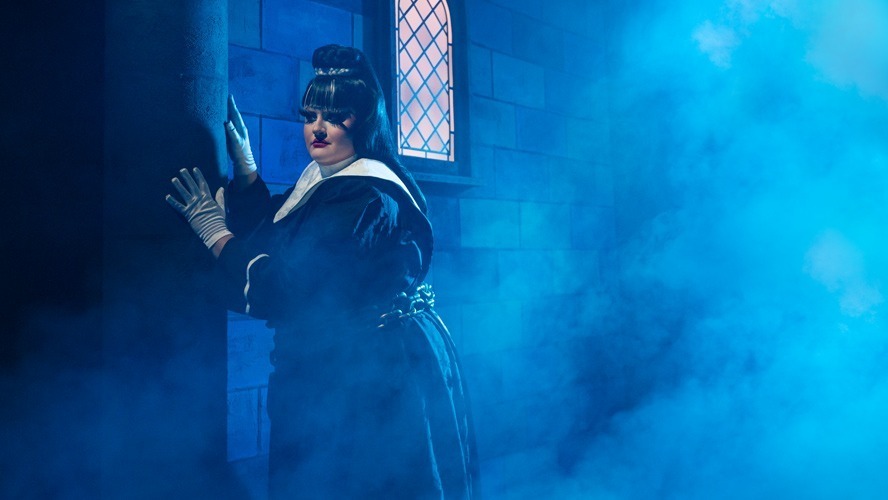 A theatrical scene featuring performers in vibrant costumes on stage at the Garrick Theatre.