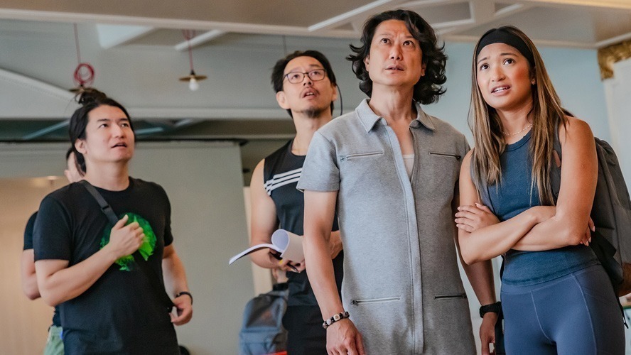 Actors in rehearsal, dressed in costumes, engaged in a dramatic scene from Death Note.
