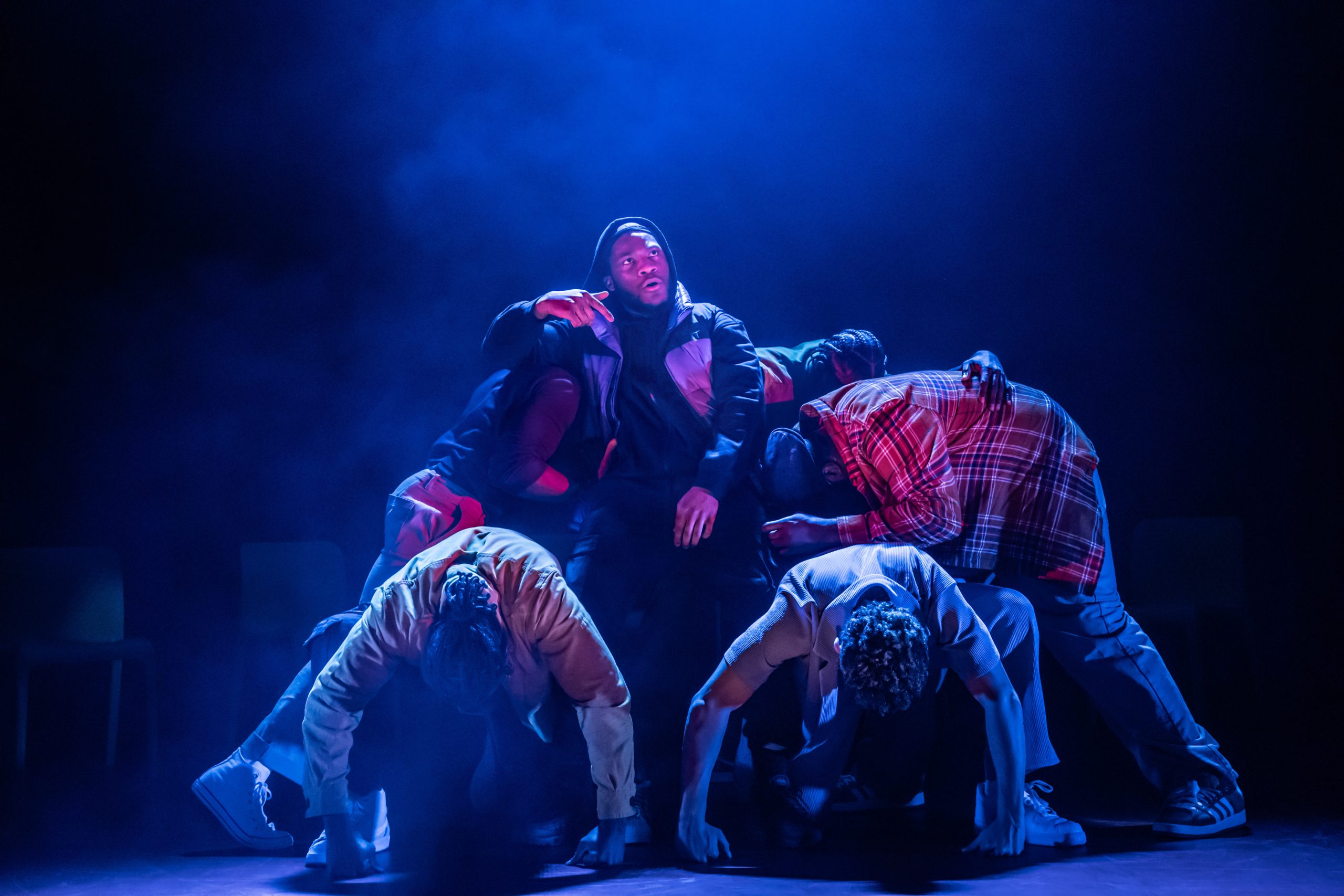 A stage scene from "For Black Boys Who Have Considered Suicide," featuring dramatic lighting and performers.