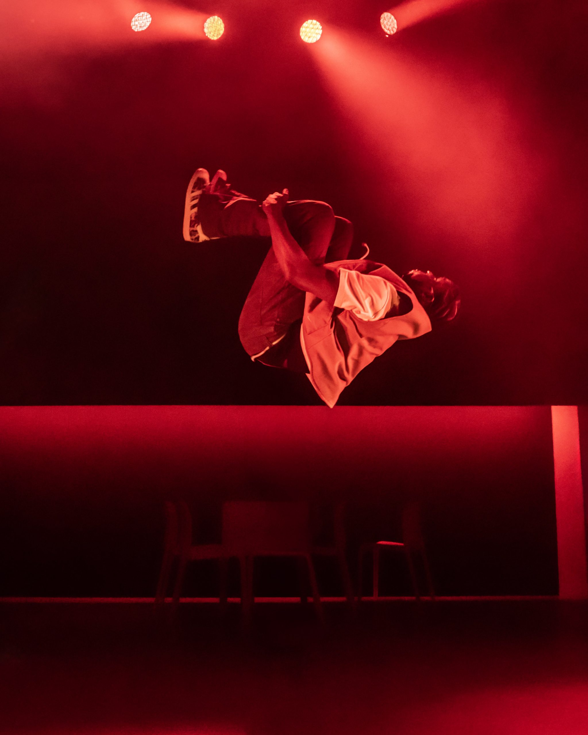 A dramatic stage scene with actors in expressive poses, illuminated by dynamic lighting at Apollo Theatre.