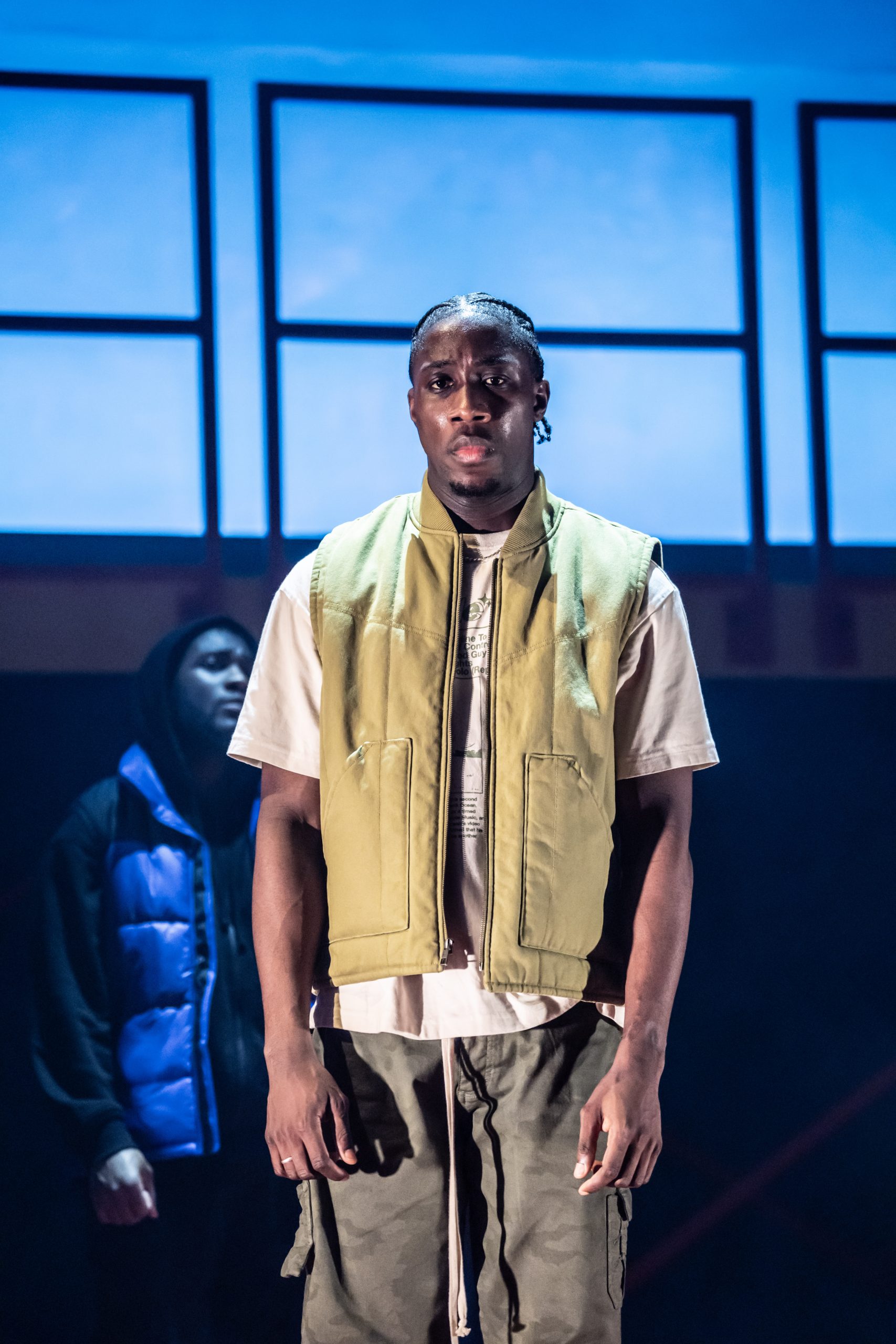 A stage scene featuring actors in dramatic poses, illuminated by focused lighting at the Apollo Theatre.