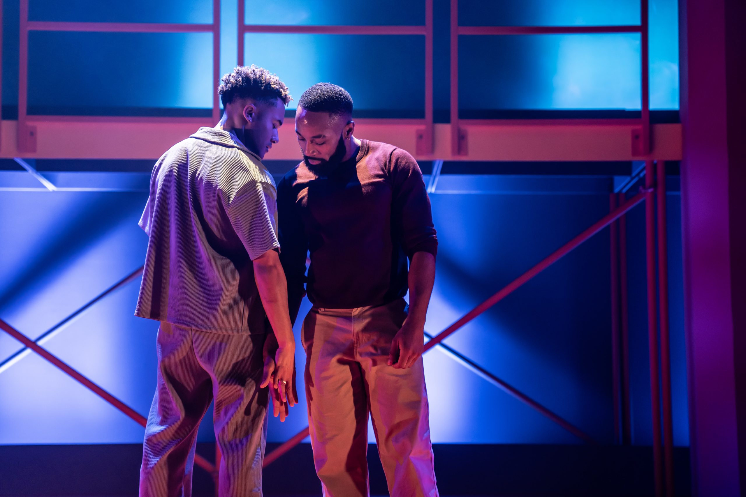 A theatrical performance scene featuring actors on stage at the Apollo Theatre, London.