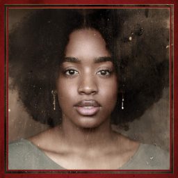 A woman with curly hair and earrings looks directly at the camera, set against a textured background.