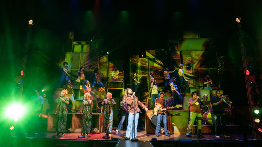 A vibrant stage set with colourful lights and a microphone stand, ready for a performance.