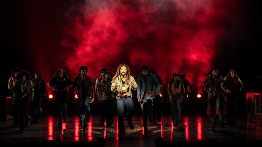 A vibrant stage set with colourful lights and musicians performing energetically in front of an audience.