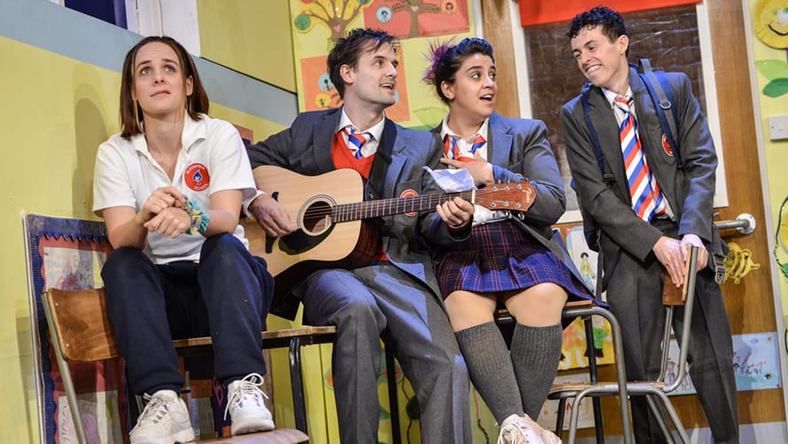 A lively stage performance at the Vaudeville Theatre, featuring actors in vibrant costumes and dramatic lighting.