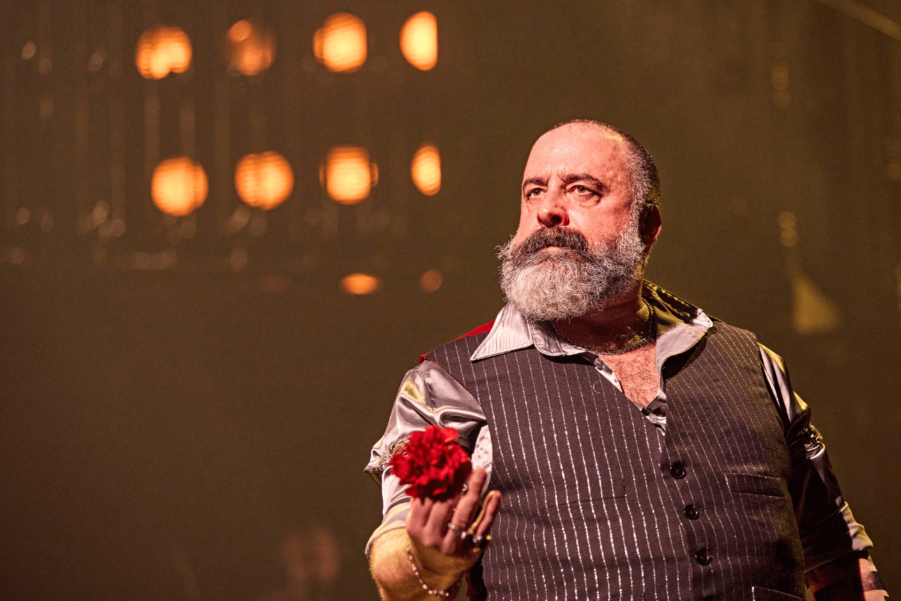 Hades looks serious as he holds a bright red flower
