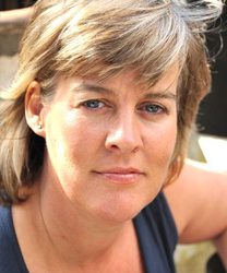 Jane Milligan smiling, wearing a navy blazer, with shoulder-length brown hair and a neutral background.
