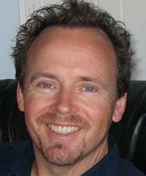 John Maher, a middle-aged man with short brown hair, wearing a blue suit and tie.