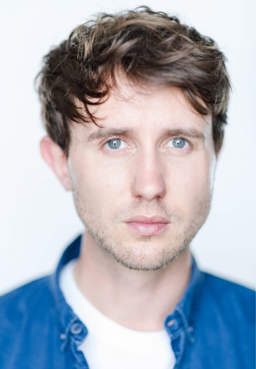 Headshot of Joshua McCord, featuring a smiling man with short brown hair and a blue shirt.