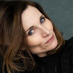 Kate Fleetwood performing on stage, wearing a black dress, with dramatic lighting and a focused expression.