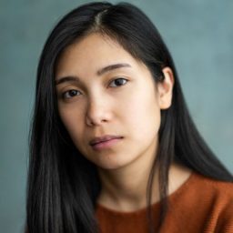 Portrait of Karen Barredo, smiling, with a blurred background of Kyoto's traditional architecture.