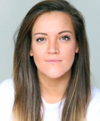 Lauryn Redding smiling, wearing a blue blouse, with long brown hair and a neutral background.