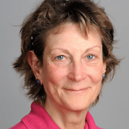 Leda Hodgson with a neutral expression, wearing a dark top, against a plain background.