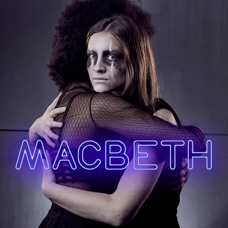 A dramatic scene from Macbeth featuring actors in period costumes on a dimly lit stage.