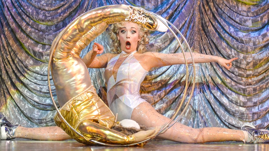 A lively scene from "Magic Goes Wrong" at the Vaudeville Theatre, featuring performers in vibrant costumes.