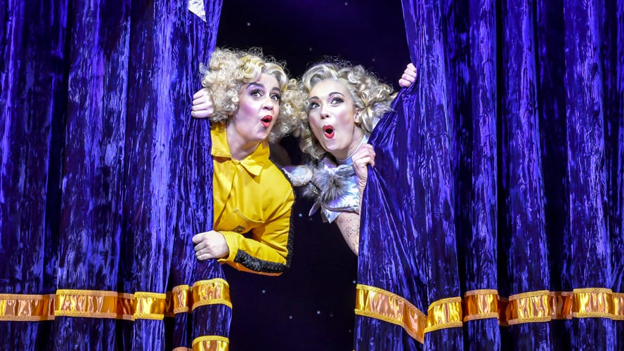 A magician performs on stage at the Vaudeville Theatre, surrounded by dramatic lighting and props.