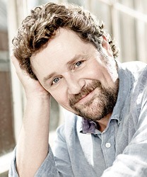 Headshot of Michael Ball, featuring a smiling expression and neatly styled hair against a neutral background.