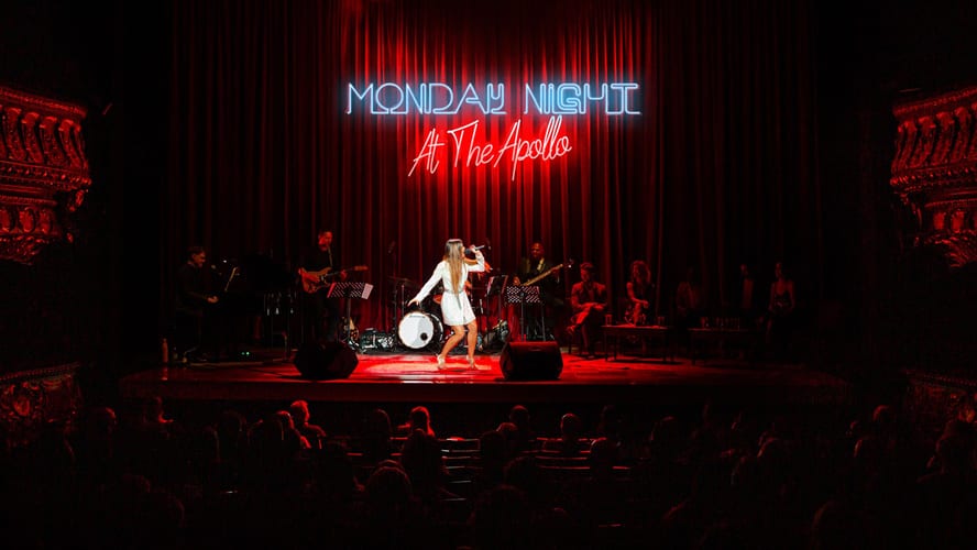 A lively stage performance at the Apollo Theatre with bright lights and an engaged audience.