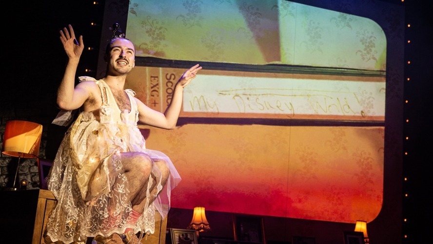 A vibrant stage with colourful lighting, featuring performers in dynamic poses and elaborate costumes.