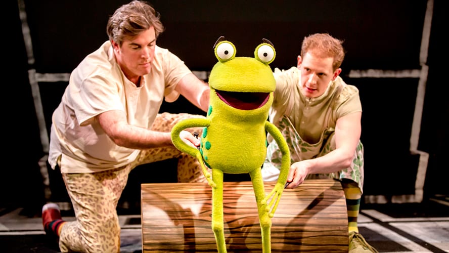 A vibrant stage scene featuring colourful animal puppets interacting with a lively audience.
