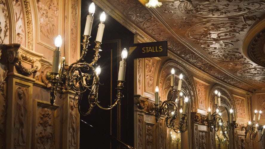 Exterior view of the Palace Theatre, featuring ornate architecture and illuminated signage at night.
