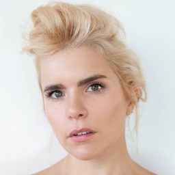 Paloma Faith performing on stage, wearing a vibrant outfit, with dynamic lighting and an engaged audience.
