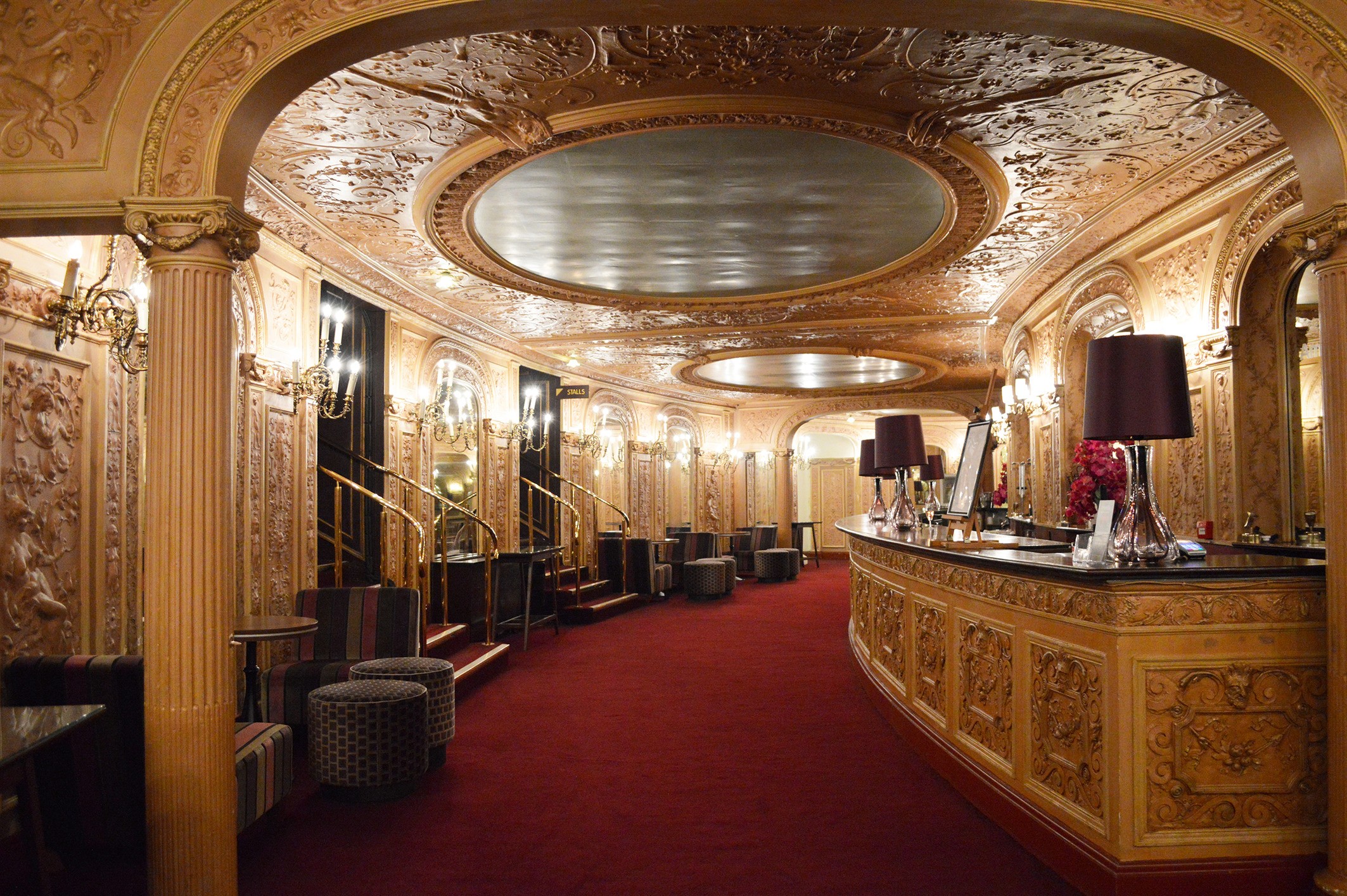 Elegant foyer of the Palace Theatre, featuring ornate decor, plush seating, and a grand chandelier.