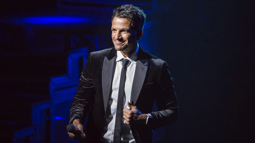 Peter Andre performing on stage in a vibrant costume at the Lyric Theatre.